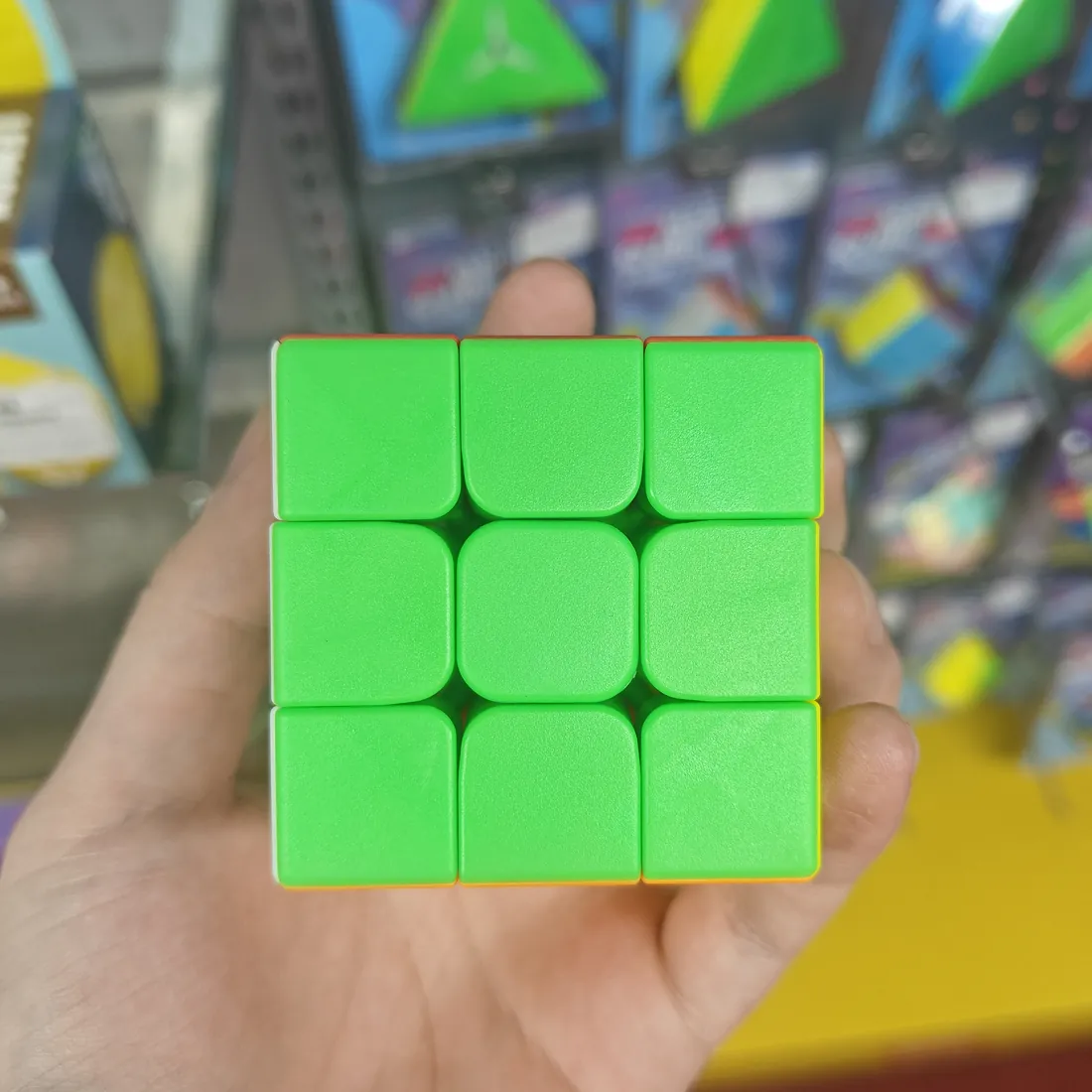 Green side of the stickerless 3×3 speed cube, held in a hand