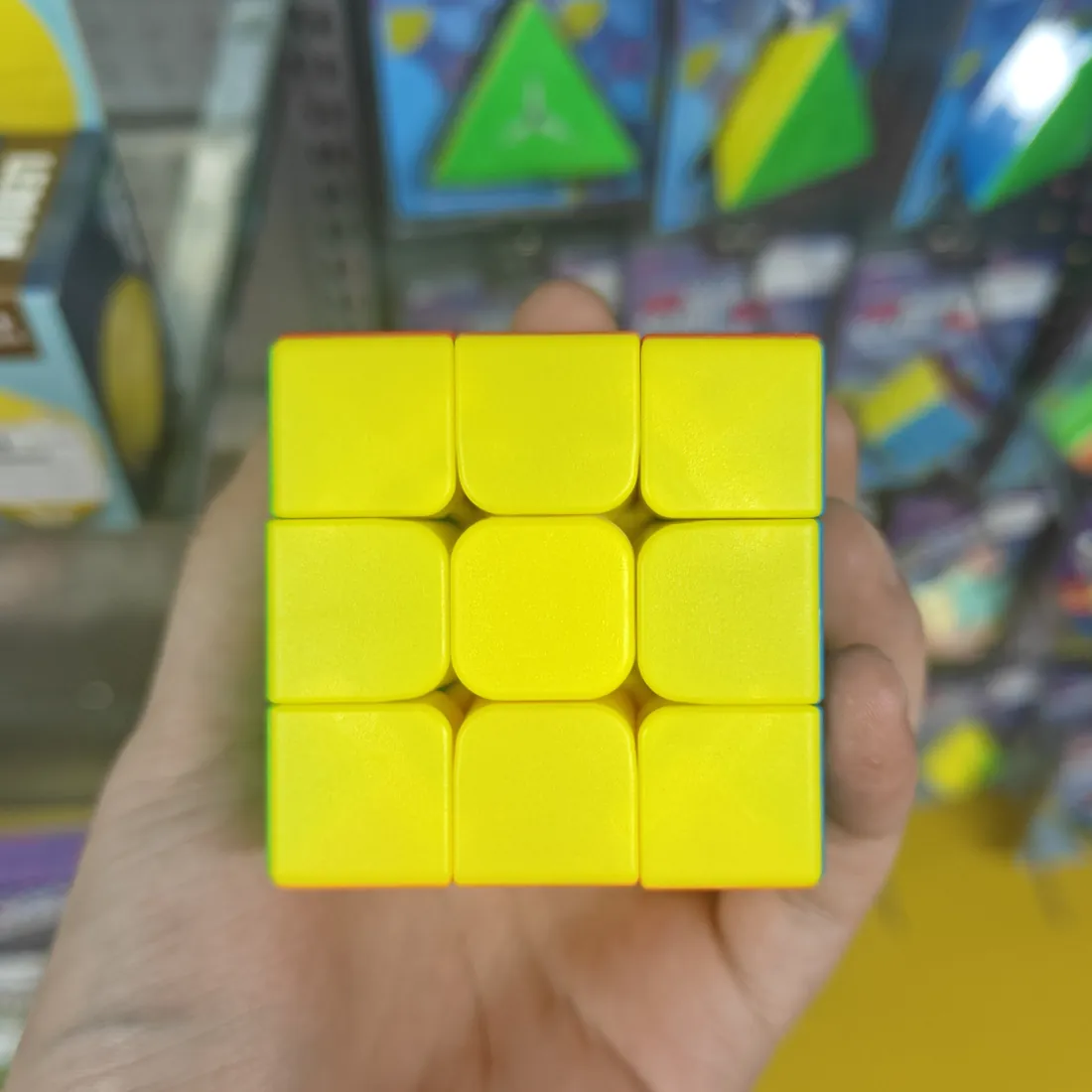 Yellow side of the stickerless 3×3 speed cube, held in a hand